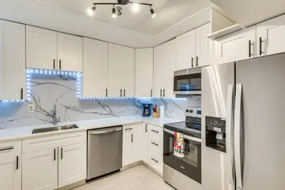 a kitchen with white cabinets and stainless steel appliances at Sunny isles Escape-1BR Condo Steps from the Beach! in Sunny Isles Beach