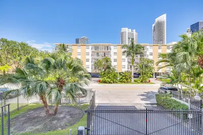 a large building with palm trees in front of it at Sunny isles Escape-1BR Condo Steps from the Beach! in Sunny Isles Beach