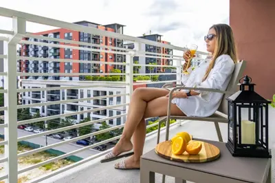 a woman sitting in a chair on a balcony with a drink at Chic Ft Lauderdale 2BR | Pool + Nightlife in Fort Lauderdale