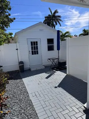 a white house with a fence and a table at Hallandale Beach Club in Hallandale Beach