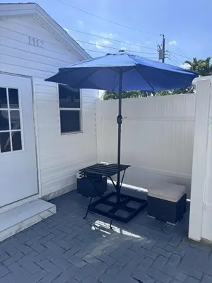 a table with a blue umbrella on a patio at Hallandale Beach Club in Hallandale Beach