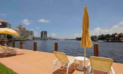 a patio with chairs and an umbrella next to the water at The Blue Octopus - 1br King Bed Condo in Fort Lauderdale