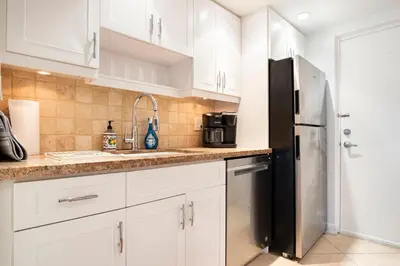 a kitchen with white cabinets and a black refrigerator at The Blue Octopus - 1br King Bed Condo in Fort Lauderdale