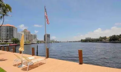 two chairs and an american flag on a dock with a river at The Blue Octopus - 1br King Bed Condo in Fort Lauderdale