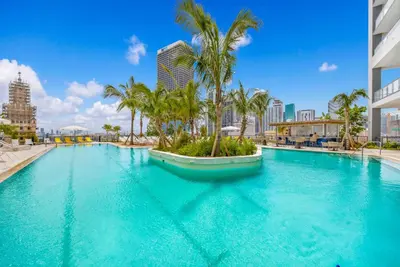 a large swimming pool with palm trees in a city at Modern Downtown Studio with city views in Miami