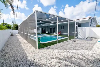 a large glass house with a swimming pool at Luxury Retreat Near Hard Rock in Joe Robbie Stadium Heliport