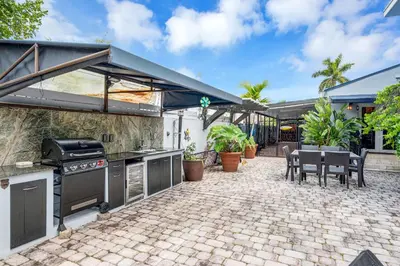an outdoor patio with a grill and a table and chairs at Magnificent Tropical Pool Home Miami SouthBrickell in Miami
