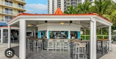 a gazebo with tables and chairs in front of a building at Ocean front paradise studio with ocean view and beach exit in Sunny Isles Beach
