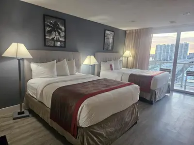 a hotel room with two beds and a balcony at Beach Studio with City View in Sunny Isles Beach