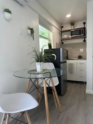 a small kitchen with a glass table and white chairs at 2 Nice and Cozy guest house in Opa-locka