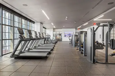a gym with a row of treadmills and machines at 3005 golden305 2BR Apt mins to Wynwood and Brickell w Pool a Gym and PS5 in Miami