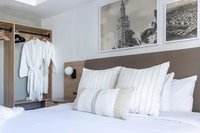 a bedroom with a white bed and a suit hanging on the wall at 3209 Apt in Heart of Downtown with Pool a Gym and Spa in Miami