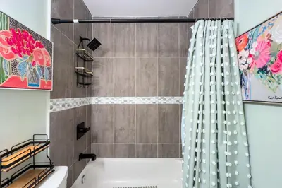 a bathroom with a tub and a shower curtain at Wynwood beautiful Art Deco home with 4 Bedroom in Miami