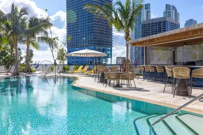 a swimming pool with chairs and tables and buildings at 3001 Miami Downtown Apt with Gym and Pool next to Kaseya Center in Miami