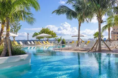 a swimming pool with palm trees and chairs at 3001 Miami Downtown Apt with Gym and Pool next to Kaseya Center in Miami