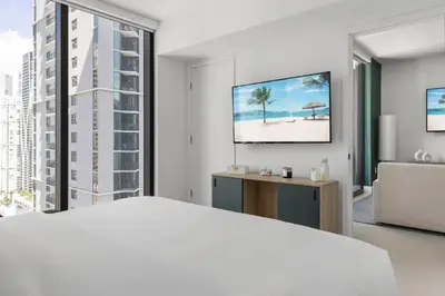 a white bedroom with a bed and a tv at 3013 Kaseya Center Apt for 4 people with Pool and Gym in Miami