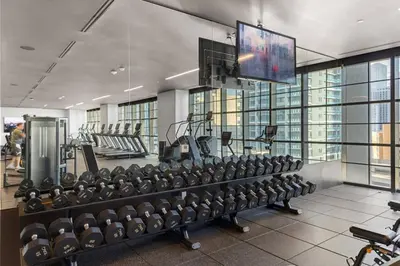 a gym with rows of exercise equipment and a flat screen tv at 3013 Kaseya Center Apt for 4 people with Pool and Gym in Miami