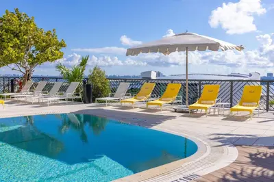 a swimming pool with chairs and an umbrella at 2704 Beautiful Downtown Apt with Gym Pool Spa Skyline Views and in front of Kaseya Center in Miami