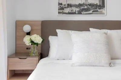 a bed with white pillows and a vase with flowers on it at 3002 Downtown Miami apt in front of Kaseya Center with Gym and Pool in Miami