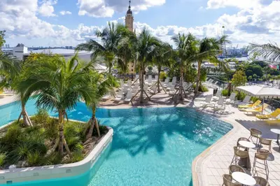 a pool at a resort with palm trees and chairs at 3002 Downtown Miami apt in front of Kaseya Center with Gym and Pool in Miami
