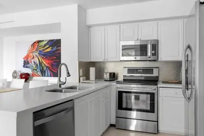 a white kitchen with a sink and a microwave at Aventura Mall Apt with Pool a Tennis Court and Free parking in Aventura