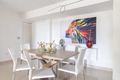 a dining room with a wooden table and white chairs at Aventura Mall Apt with Pool a Tennis Court and Free parking in Aventura