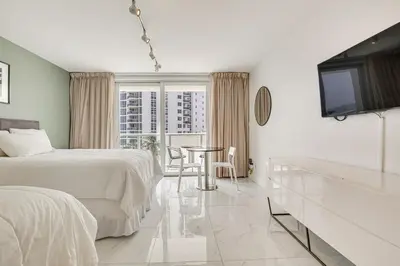 a bedroom with a bed and a table and a tv at Sunny Isles Beach Ocean View Studio with Balcony in Sunny Isles Beach