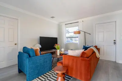 a living room with two blue chairs and a television at Tropical Retreat on Sheridan l Near Beach and Parks in Hollywood