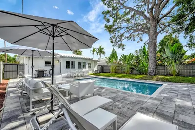 a patio with chairs and an umbrella next to a pool at Palm Haven in Fort Lauderdale