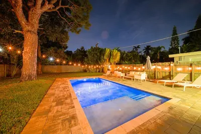 a swimming pool in a backyard at night at Palm Haven in Fort Lauderdale