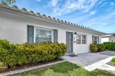 a white house with bushes in front of it at Palm Haven in Fort Lauderdale