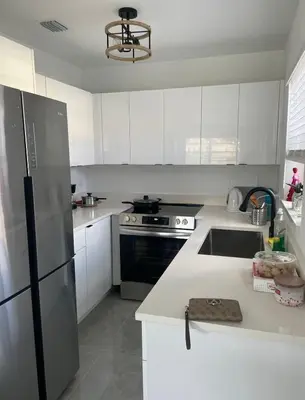 a kitchen with white cabinets and a stainless steel refrigerator at USA Star Hostel in Hallandale Beach