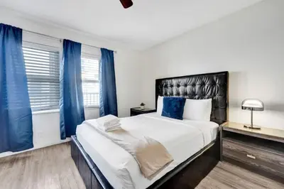 a bedroom with a large bed with blue curtains at Eden Collection Studio Steps to beach in Fort Lauderdale