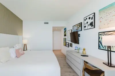 a white bedroom with a bed and a tv at Lyfe Resort & Residences By OceanMiami in Hollywood