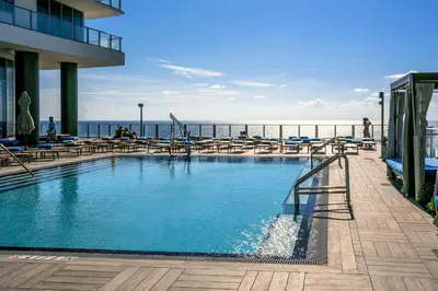 a swimming pool with lounge chairs and the ocean at Lyfe Resort & Residences By OceanMiami in Hollywood