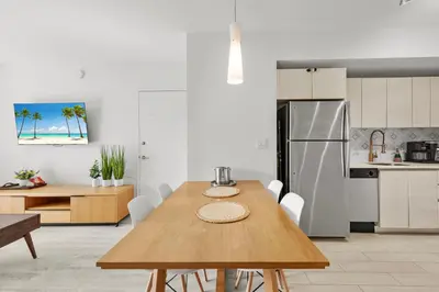 a kitchen and dining room with a table and a refrigerator at Coastal Luxe Residences - Premium Suites with Pool and Water Views in Hallandale Beach