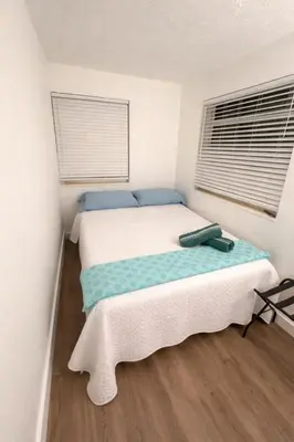 a bedroom with a bed with a blanket and two windows at La Mare Fort Lauderdale Airport in Fort Lauderdale
