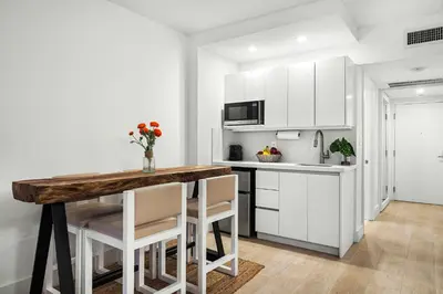 a kitchen with a wooden table and white cabinets at Studio Residence at Roney -1128 in Miami Beach
