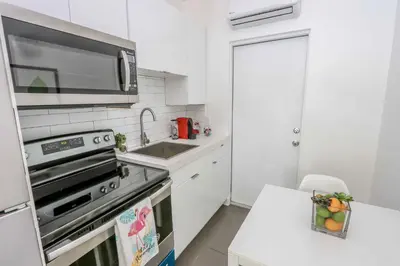 a white kitchen with a stove and a microwave at Mimo Bungalows By Renzzi in Miami