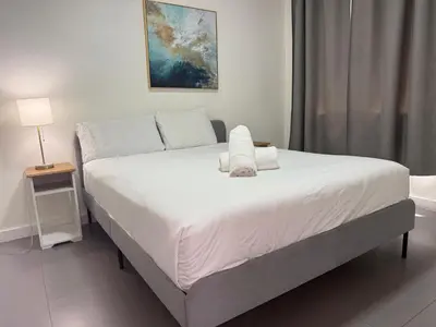 a bedroom with a large bed with white sheets at Wynwood Bungalows By Renzzi in Miami