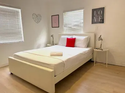 a bedroom with a large white bed with a red pillow at Wynwood Bungalows By Renzzi in Miami