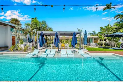 a swimming pool with blue umbrellas and chairs at Waterfront Heated pool Lime Key Two in Fort Lauderdale