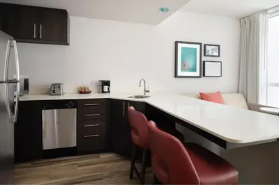 a kitchen with a sink and a counter with red chairs at Residence Inn by Marriott Miami Beach Surfside in Miami Beach
