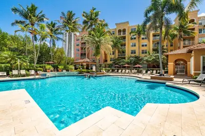 a swimming pool with palm trees and a building at Yacht Club Miami Suite 1BR and 1BA with Pool FREE Parking Gym & Jacuzzi in South Island