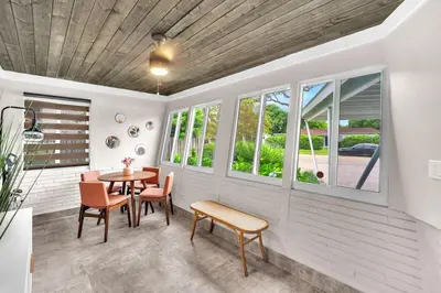 a porch with a table and chairs and windows at The Frolics -Stunning Wilton Manors Pool Home in Fort Lauderdale