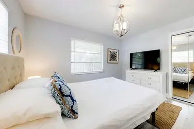 a white bedroom with a bed and a tv at Unique 2 House Rental 3 Mi to Beach and Boardwalk in Hollywood