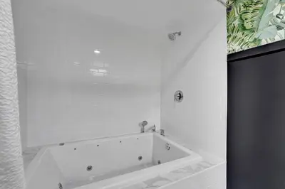 a white bath tub in a white tile bathroom at Heated Saltwater Pool Family & Pet-Friendly Oasis in Fort Lauderdale