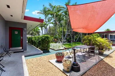 a patio with a table and a red umbrella at 1BR Studio Parking, BBQ, Garden In Hollywood in Hollywood