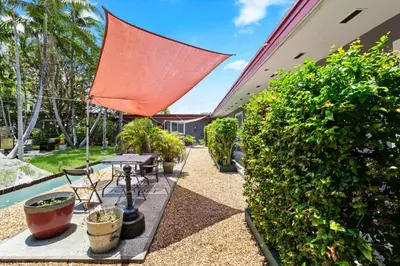 a patio with a table and a red umbrella at 1BR Studio Parking, BBQ, Garden In Hollywood in Hollywood
