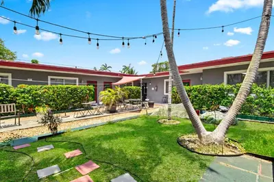 a yard with palm trees in front of a house at Bright 2BR Getaway | BBQ, Garden & Parking in Hollywood